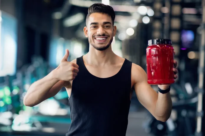 man holding lactose-free protein powder while standing in GYM